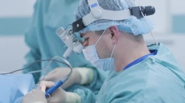 Operation of removing tonsils. tonsillectomy under deep anesthesia, using latest devices, cold plasma method, cuts swelling in throat, doctor works with new probe, medical headlamp, surgical loupes