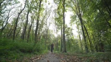 Orman yolunda bisikletli ve gözlüklü bir adamın ön görüntüsü. Dağ bisikletli bir adam yaz gündoğumunda ormanda gezer..