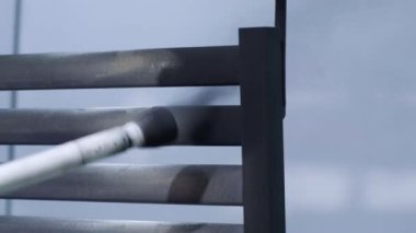 Bir işçi, paslanmaz çelik bir yapıyı havalı sprey tabancayla boyuyor. Kuru boyama yöntemi.