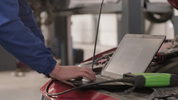 자동차의 컴퓨터 진단, 젊은 기계공 전문의 남성은 기지국에서 차창이 열려 있는 차를 수리하면서 노트북 기술을 사용 한다 — 비디오