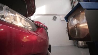 İşçi bir arabanın ışıklandırma sisteminin farlarını kontrol eder ve ayarlar. Otomatik onarım servisi.