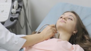 Klinikte genç kadın tiroid bezinin ultrason taraması yapılıyor. Kadın doktor hastanın boynunda ultrason sensörü çalıştırıyor..