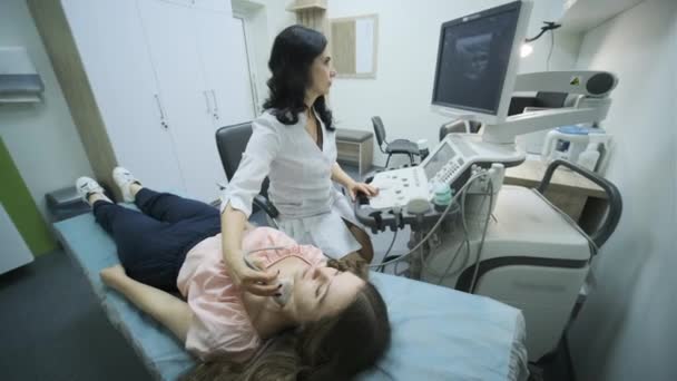 年轻女性甲状腺超声扫描诊断在临床上的应用 女医生在病人脖子上安装超声波传感器 — 图库视频影像