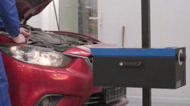 İşçi bir arabanın ışıklandırma sisteminin farlarını kontrol eder ve ayarlar. Otomatik onarım servisi.