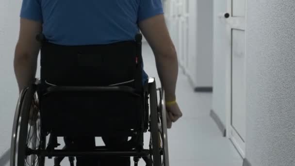 一个坐轮椅的男人开车穿过走廊 一个残疾人在医院里到处走动 — 图库视频影像