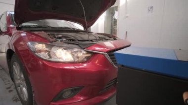 İşçi bir arabanın ışıklandırma sisteminin farlarını kontrol eder ve ayarlar. Otomatik onarım servisi.