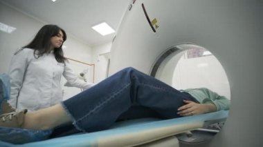 Kadın hasta, modern tıp kliniğinde bir radyologun gözetiminde CT ya da MRI taramasından geçiriliyor. Tomografide ya da MR tarama yatağında yatan hasta, makinenin dışına çıkıyor..