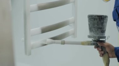 Bir işçi, paslanmaz çelik bir yapıyı havalı sprey tabancayla boyuyor. Kuru boyama yöntemi