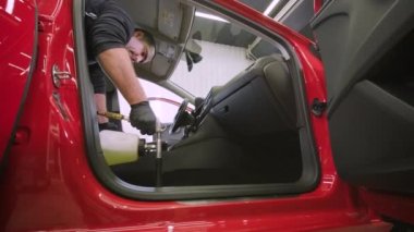Profesyonel araba temizliği. Yıkama, kuru temizleme ve kabin temizliği. Cesedin derin temizliği, koltuk temizliği. Araba yıkamada köpük silerken. Araba panelini tozdan temizliyorum. Elektrikli süpürge.