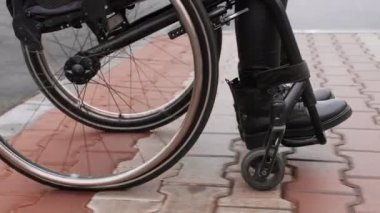 A person with a disability moves along the street in a wheelchair