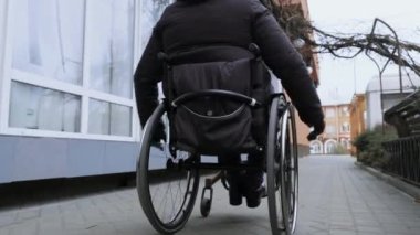A person with a disability moves along the street in a wheelchair