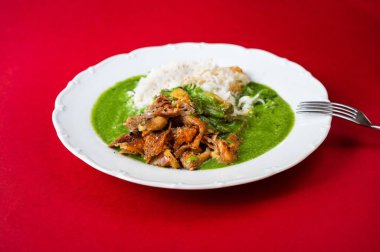 Öğütülmüş tavuk eti, ıspanak soslu pilav kırmızı arka planda çatal, yakın plan..