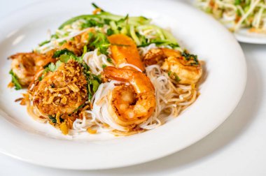 Kızarmış soğanlı haşlanmış karides, yeşil atış, otlar ve beyaz tabakta dilimlenmiş kohlrabi, beyaz arka planda salatayla birlikte ikinci tabağın bir parçası. Asya tarzı yemekler..