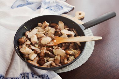 Ahşap masada kızartma tavasında leziz kızarmış mantarlar.