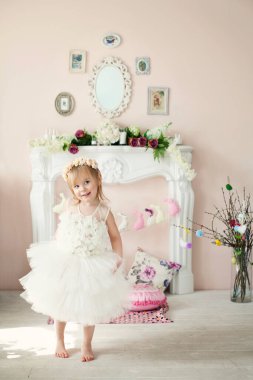 Çiçekli çelenk ve pofuduk etek giyen, şöminenin yanında dans eden güzel bir kız. Paskalya konsepti