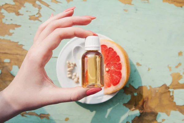 Elinde greyfurt tohumu özü olan bir şişe, greyfurt parçaları, tohumlar. Covid, doğal antibiyotik ve antiviral ilaç tedavisi için ilaçlar. Narenciye, C vitamini Coronavirüs salgını ile bağışıklık kazanma durumu.