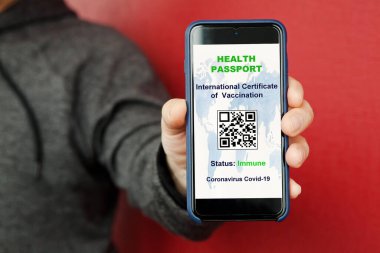 Ekranda uluslararası aşı sertifikası olan akıllı telefon COVID-19 için dijital aşı pasaportu olan bir adam var. Sağlık Pasaportu Konsepti, Coronavirüs salgını durumu