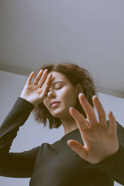 Young beautiful woman closing her face with hand.