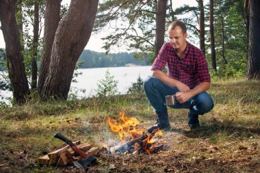 Kamp ateşinin yanında oturan yürüyüşçü. 