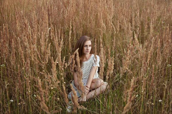 Beautiful young woman sitting in grass