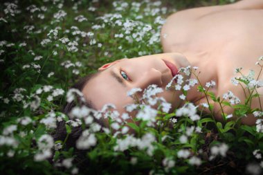 Çiçeklerle çimenlerde yatan genç adam