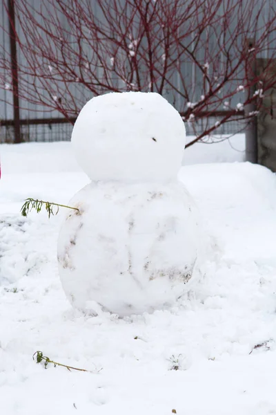 Deux grosses boules de neige se dressent les unes sur les autres près du buisson — Photo