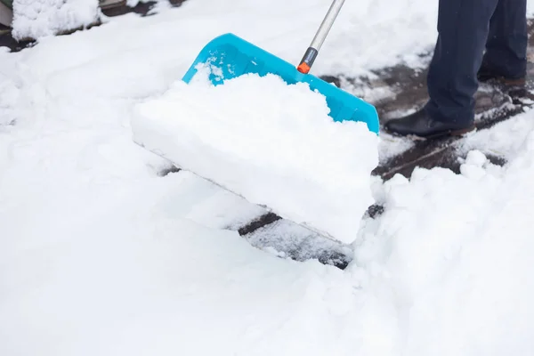 男は大きな青いシャベルで雪をきれいにする — ストック写真