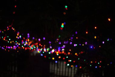 Birçok parlak bulanık renkte çelenk ışıkları siyah bir arkaplanda.