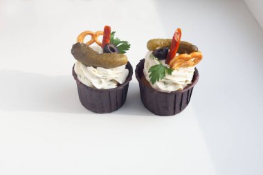 Salatalık turşulu iki muffin, beyaz arka planda kraker duruyor ve gölgesi var. Bira içen bir adam için alışılmadık bir aperatif.