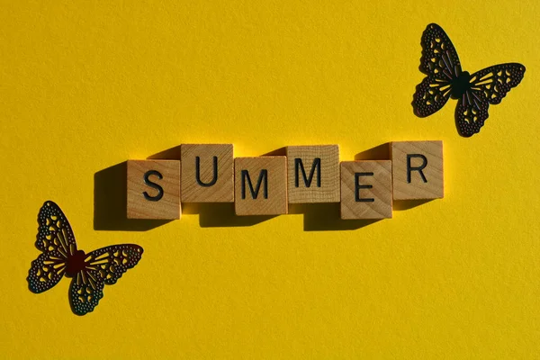 夏には木製のアルファベット文字で明るい黄色の背景に2つの蝶の形 — ストック写真