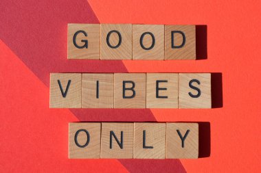 Sadece Good Vibes, kırmızı arkaplanda izole edilmiş ahşap alfabe harflerindeki pozitif ifade.