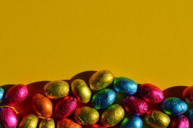 Renkli folyo, Paskalya yumurtalarını fotokopi alanı ile birlikte parlak sarı arka plana sarmış.