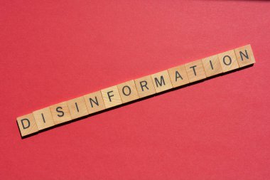Disinformation, word in wooden alphabet letters isolated on red background with copy space clipart