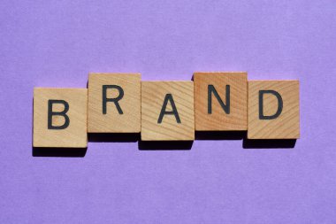 Marka, ahşap alfabedeki harfler mor arkaplanda sancak başlığı olarak izole edilmiş.