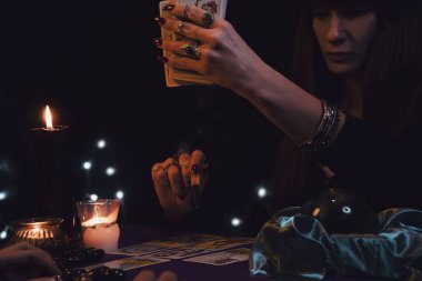 Tarot kartlarında geleceği okuyan kadın rünleri, kristal küreyi ve siyah mumu parçalıyor.