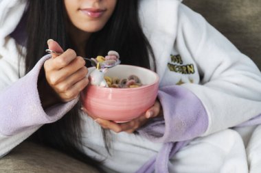 Tek boynuzlu at kürklü genç bir kadın kahvaltıda renkli mısır gevreği ve portakal suyu yiyor.