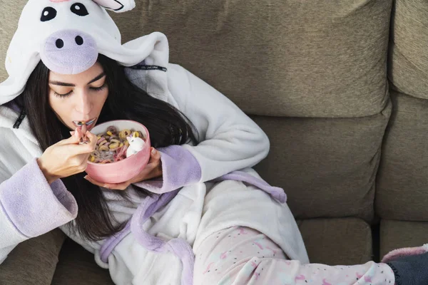 Tek boynuzlu at kürklü genç bir kadın kahvaltıda renkli mısır gevreği ve portakal suyu yiyor.