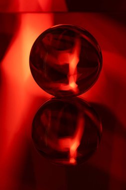 Aynadaki cam kristal küre kırmızı desenli ışık fraktalları siyah arka planda boyuyor.