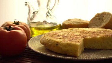 Domatesli İspanyol tortillası, sarımsak, ekmek, soğan ve açık arkaplanda bir kavanoz zeytinyağı.
