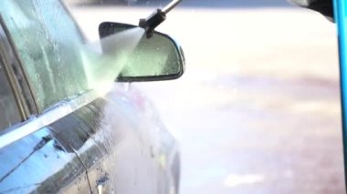 Genç İspanyol adam siyah spor arabasını bir oto yıkamada temizleyip yıkıyor.