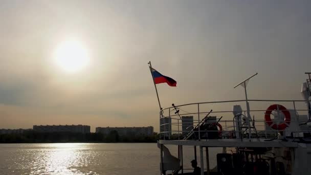 ロシアの旗が桟橋の川の船に手を振っている夕日には船の男のシルエットが見える — ストック動画