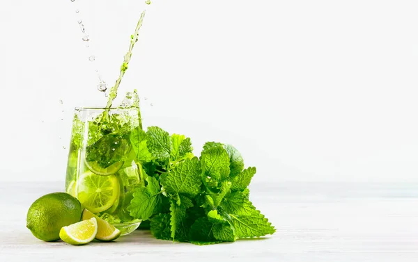 Mojito bardağa hafif arka planda su sıçraması, limonlu iki jet, bir demet nane ve buz doldurur. Mojito seti..