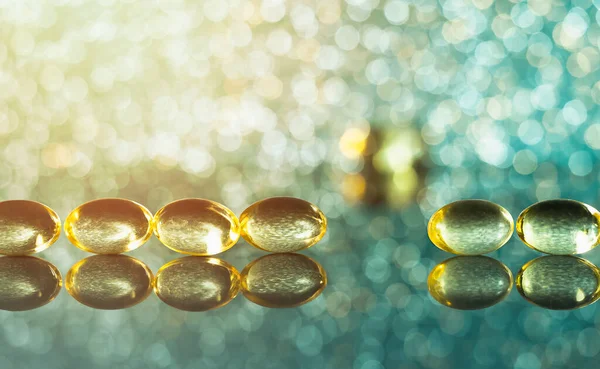 Cam üzerindeki balık yağı kapsüllerinin fotografı. Bokeh ve parıltı ile.