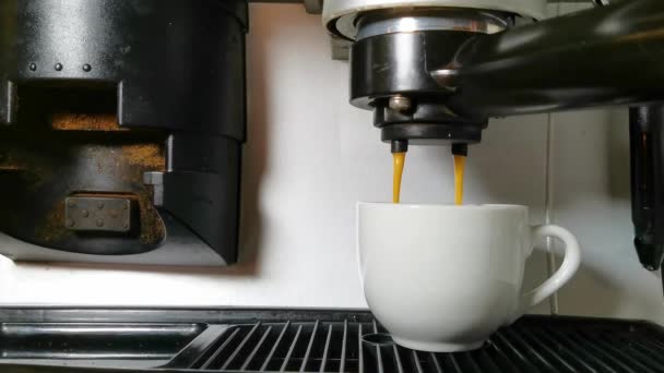 La máquina de café vierte el café en la taza. derrames de café sobre el borde de la taza — Vídeos de Stock