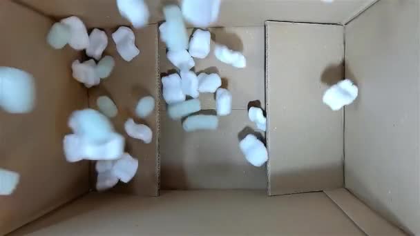 Zöld hab gumi és fehér styrofoam töltőanyag esik egy kartondobozba — Stock videók