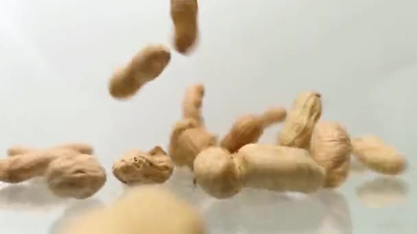 Φιστίκια πέφτουν από πάνω στο τραπέζι. Πτώση αραχίδων στη φλούδα — Αρχείο Βίντεο