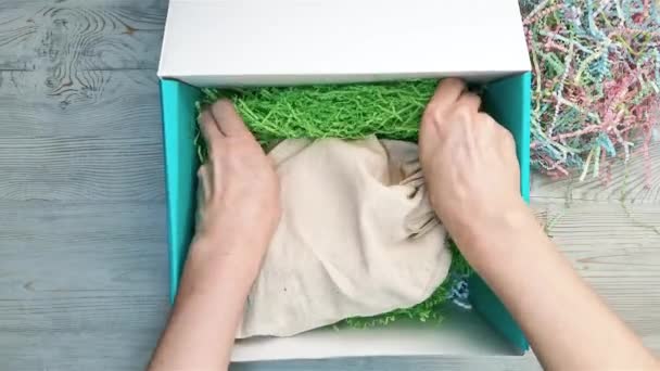 Weibliche Hände packen in einen Füller und eine Tasche mit einem Geschenk — Stockvideo
