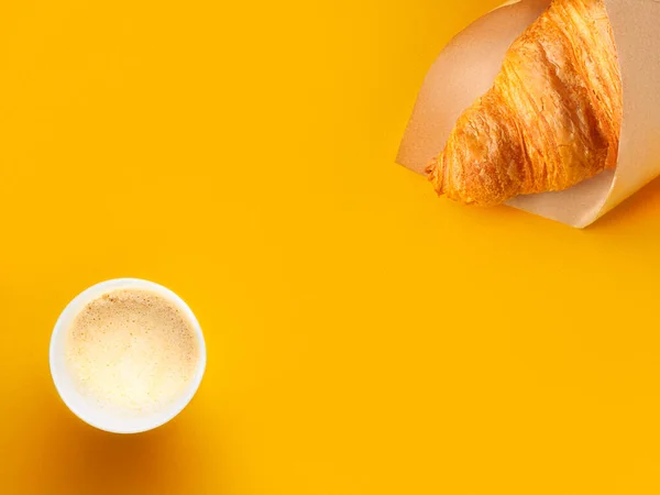 Taza de papel de café y croissant en papel artesanal sobre papel naranja brillante — Foto de Stock