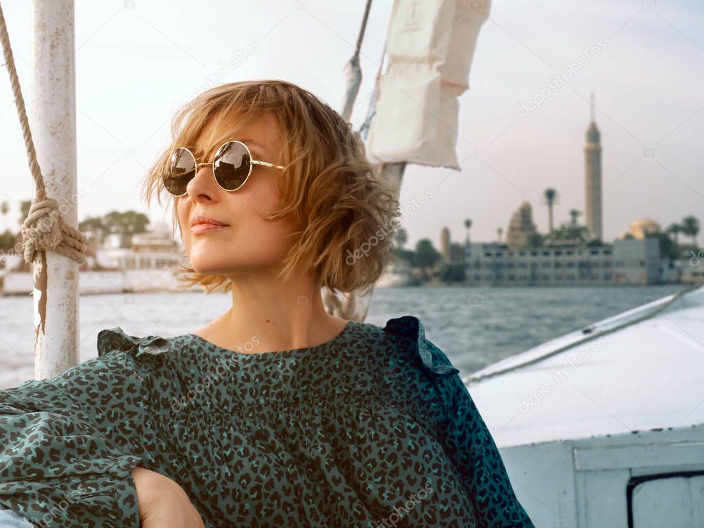 woman in a green dress and sunglasses sits beautifully in a boat - Felucca