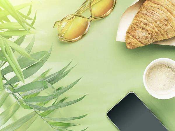 Taza de papel de café, croissant, teléfono, gafas de sol y hojas de palma Fotos De Stock Sin Royalties Gratis